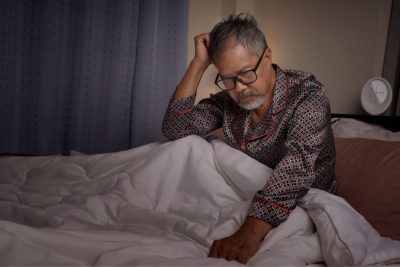 Photo an elderly man with a depressed and stressed white beard sat in bed from insomnia