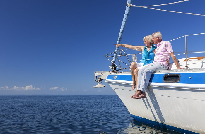 A happy senior couple sitting on the side of a sail boat