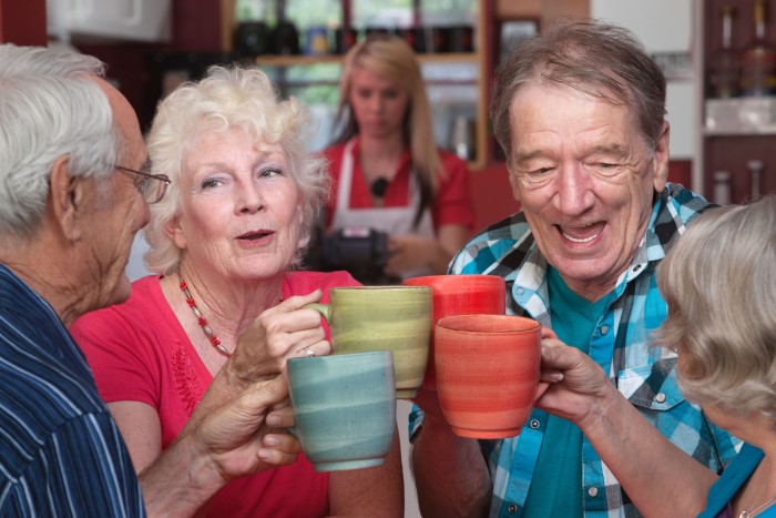 Group of four happy seniors with mugs toasting