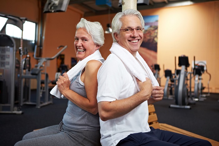 happy senior couple with towels in a gym
