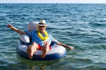 59126621 - senior man with hawaii shirt and flowers floating at the sea