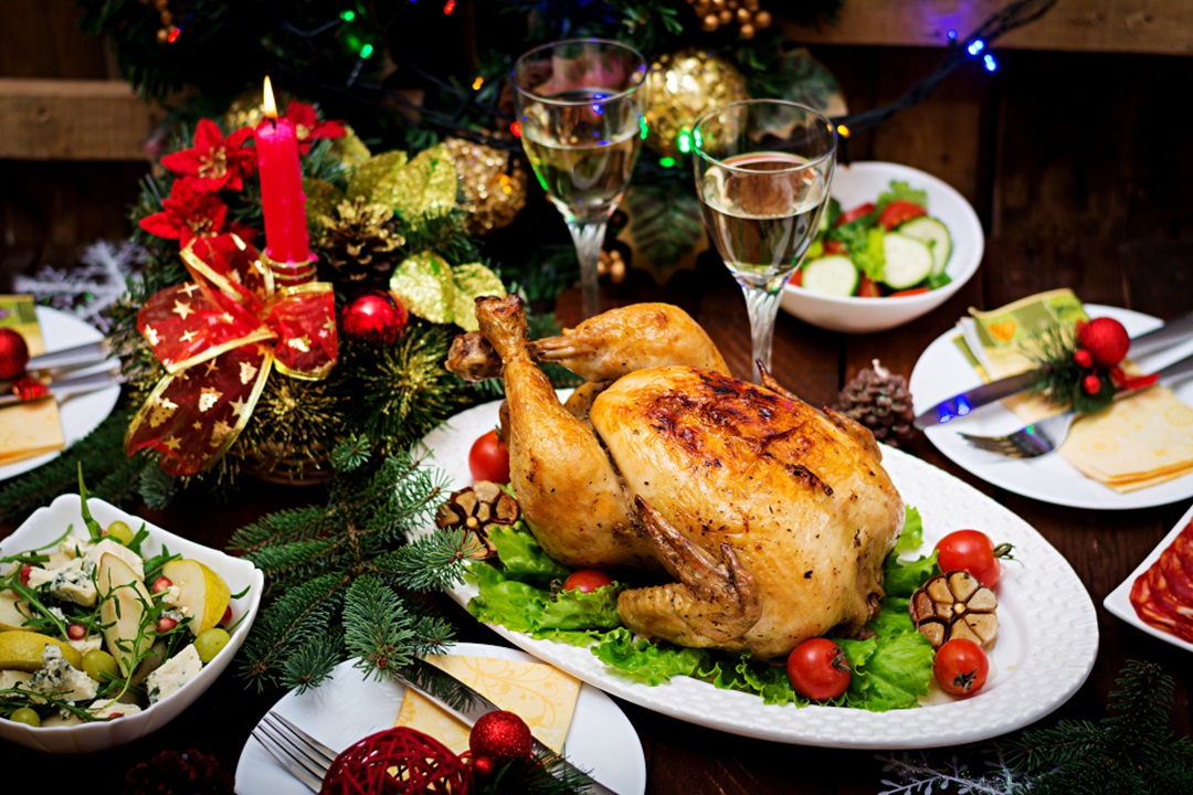 Free photo Christmas table served with a turkey, decorated with bright tinsel and candles