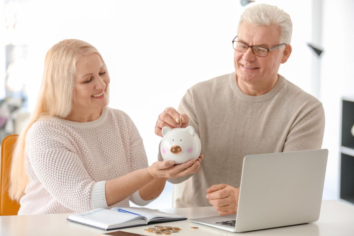 Senior couple putting coin into a piggy bank for retirement savings
