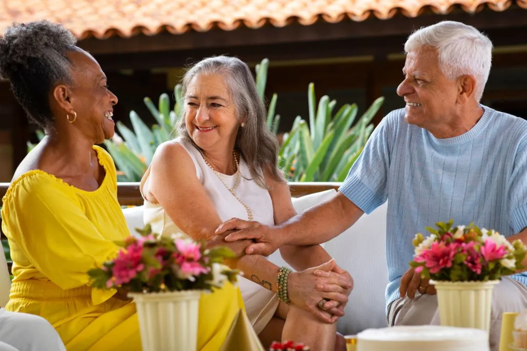 1. A senior couple engaged in a lively conversation with their friends, sharing smiles and enjoying each other's company.