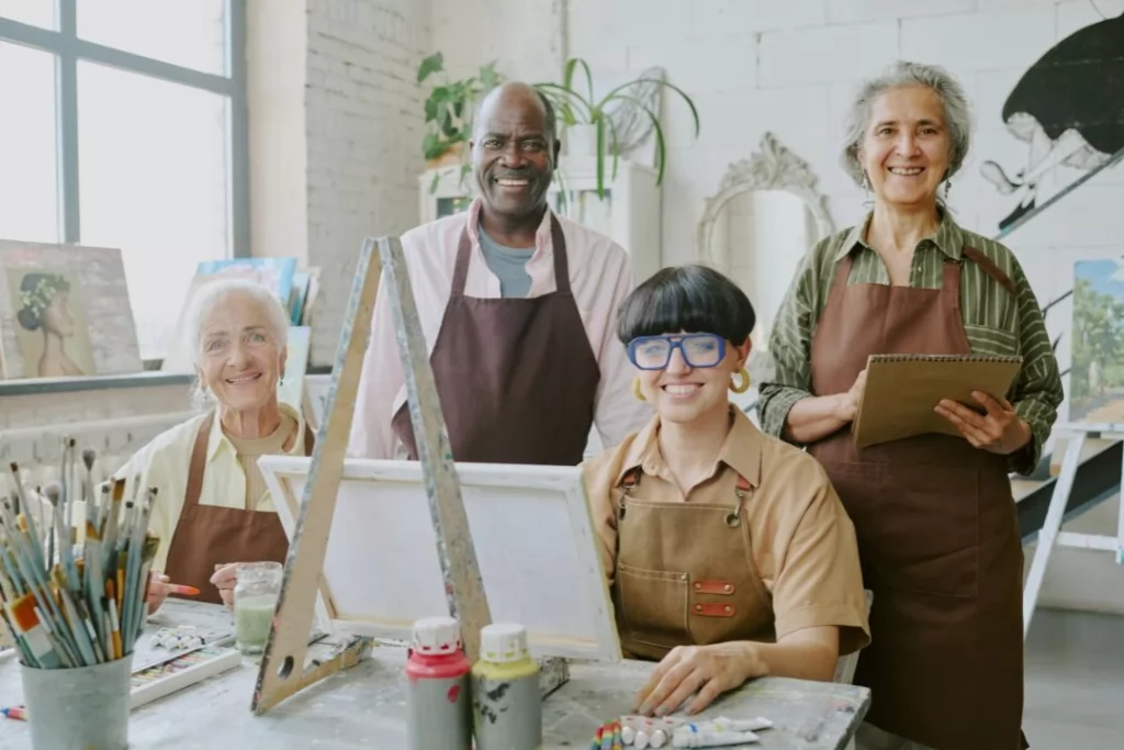  diverse group of individuals collaborating in a vibrant art studio, surrounded by various art supplies and creations