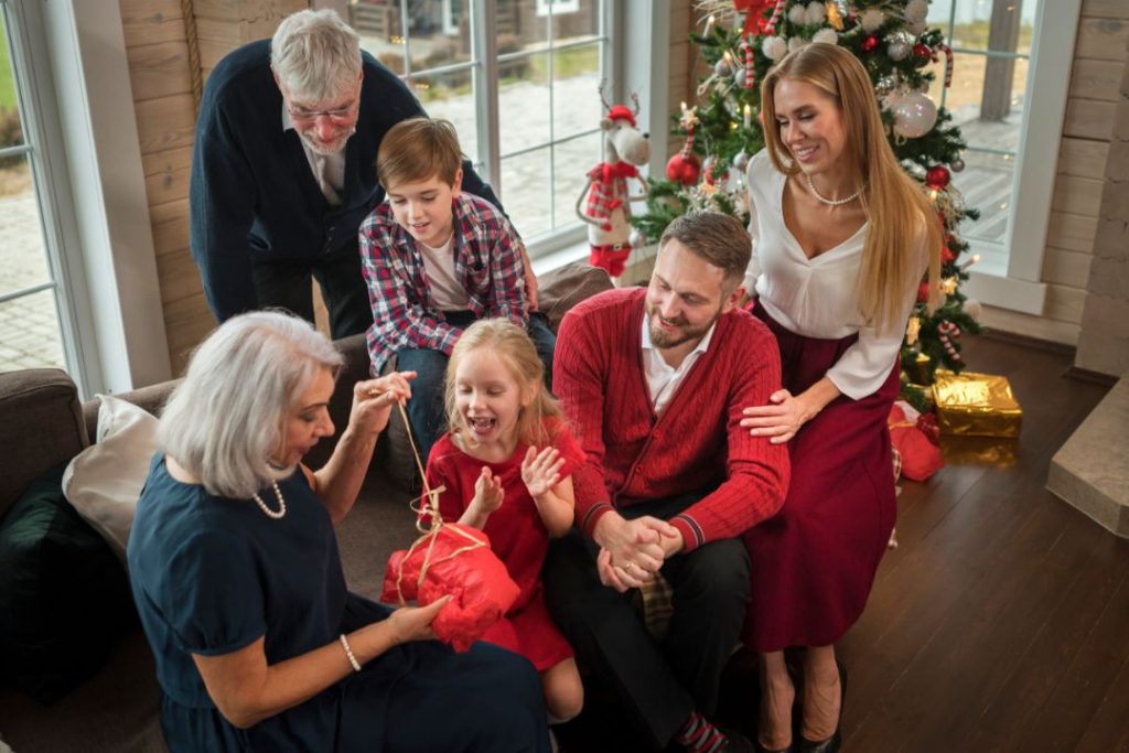 A family joyfully gathered around a beautifully decorated Christmas tree, surrounded by colorful presents.