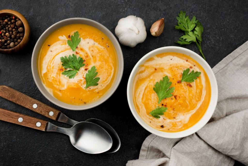 Two bowls of soup garnished with fresh herbs and spices, showcasing a vibrant and appetizing presentation.