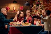 A group of people joyfully toasting with glasses at a festive Christmas dinner table adorned with decorations.