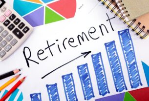 Calculator, colored pencils, notebooks, and charts surrounding a paper with a blue bar graph and the word "Retirement" written above it.