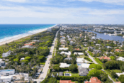 Aerial view of a residential neighborhood with houses and streets, overlooking a vast ocean in the background