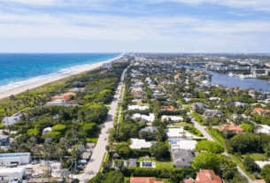 Aerial view of a residential neighborhood with houses and streets, overlooking a vast ocean in the background