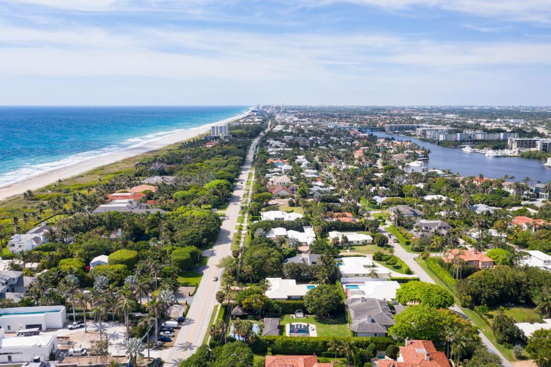 Aerial view of a residential neighborhood with houses and streets, overlooking a vast ocean in the background
