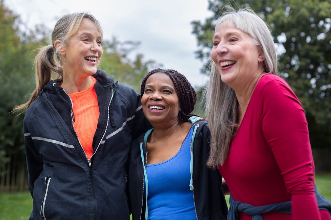 A diverse group of happy seniors walking in a park, laughing and enjoying each other’s company